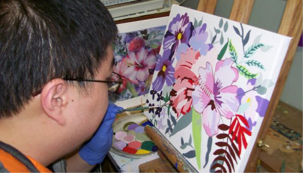 Boy painting flowers on a canvas